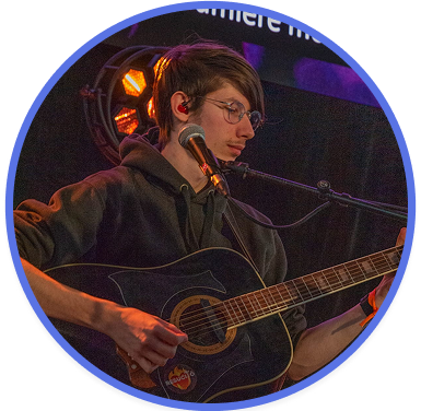 Photo de profil de Léo Batardon, on le voit avec une guitare à la main et un micro devant la bouche.